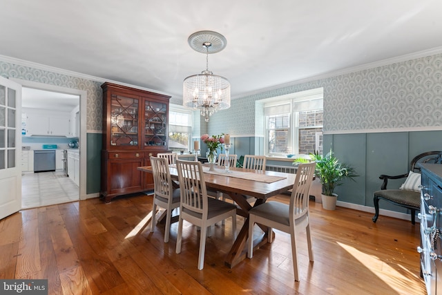 dining room featuring ornamental molding, light hardwood / wood-style floors, and a notable chandelier