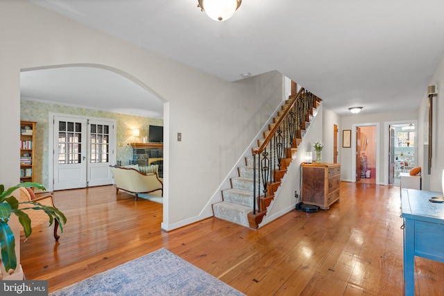 entrance foyer featuring hardwood / wood-style flooring, a stone fireplace, and crown molding