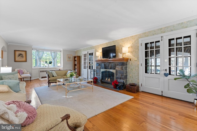 living room featuring a stone fireplace, light wood-type flooring, and french doors