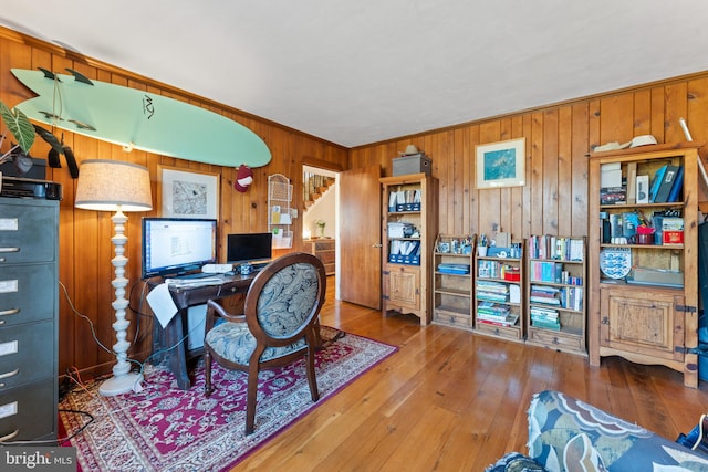 office area featuring hardwood / wood-style flooring, ornamental molding, and wooden walls