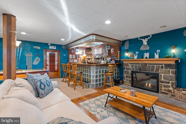 living room with a fireplace, indoor bar, and hardwood / wood-style flooring