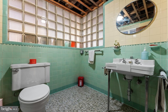 bathroom featuring toilet, tile walls, and a healthy amount of sunlight