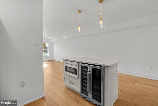 kitchen with pendant lighting, a center island, light wood-type flooring, white cabinetry, and beverage cooler