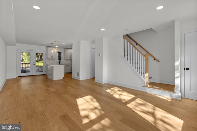 unfurnished living room featuring french doors and light wood-type flooring