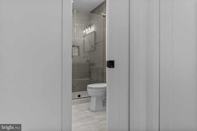 bathroom featuring toilet and a shower with shower door