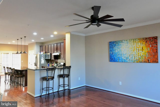 kitchen featuring kitchen peninsula, a kitchen breakfast bar, stainless steel appliances, decorative light fixtures, and dark hardwood / wood-style floors