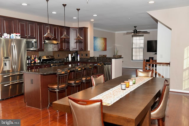 dining room with crown molding, sink, ceiling fan, and dark wood-type flooring