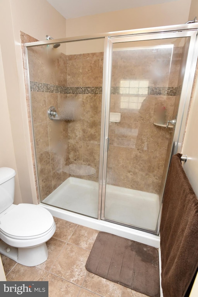 bathroom with tile patterned floors, a shower with door, and toilet