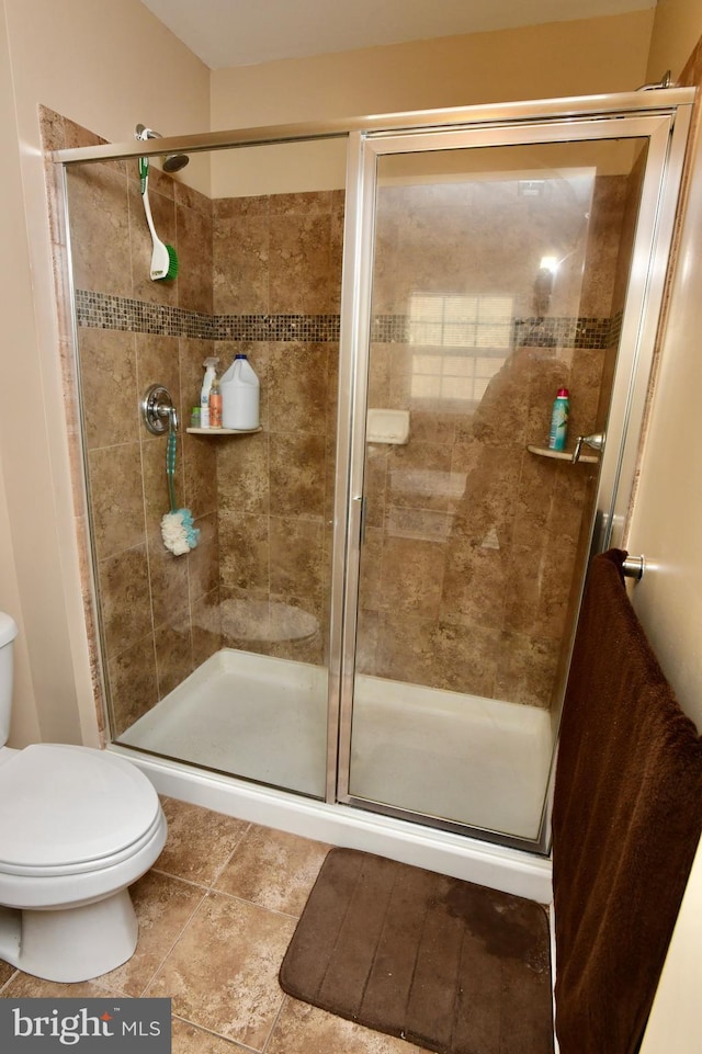 bathroom featuring toilet and a shower with shower door