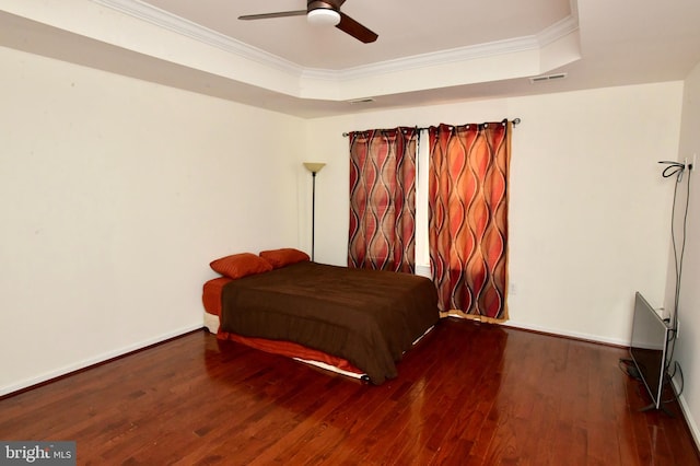 bedroom with a tray ceiling, ceiling fan, hardwood / wood-style floors, and crown molding