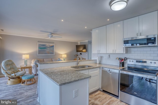 kitchen with kitchen peninsula, stainless steel appliances, sink, light hardwood / wood-style flooring, and white cabinetry