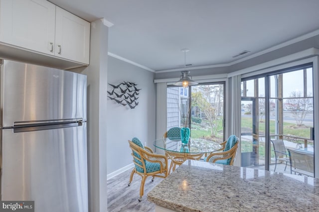 dining space with plenty of natural light, light hardwood / wood-style floors, and ornamental molding