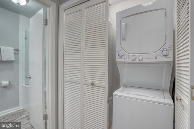 laundry room with light hardwood / wood-style floors and stacked washer / drying machine