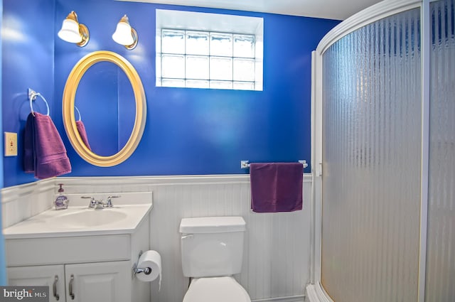 bathroom with vanity, toilet, and a shower with door