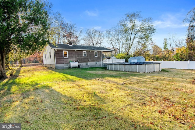 rear view of property featuring a yard and a covered pool