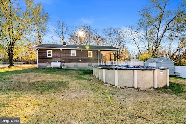 back of house with a lawn, a shed, and a covered pool