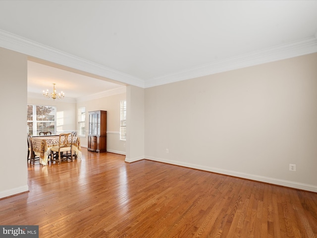 unfurnished room featuring crown molding, wood-type flooring, and an inviting chandelier