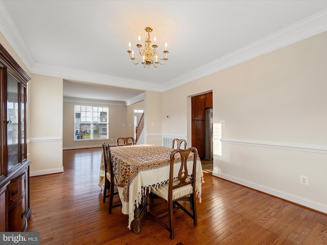 dining area featuring ornamental molding, dark wood-type flooring, and a notable chandelier