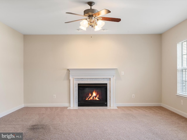 unfurnished living room with ceiling fan, light colored carpet, and a premium fireplace