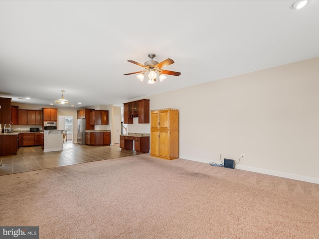 unfurnished living room featuring ceiling fan, light tile patterned floors, and sink