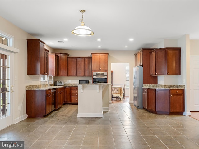 kitchen featuring pendant lighting, plenty of natural light, light stone counters, and appliances with stainless steel finishes