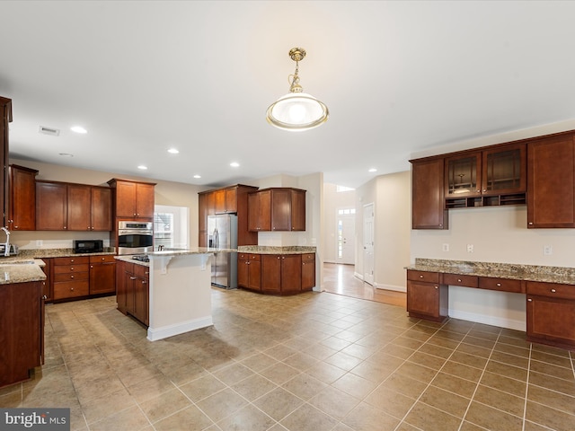 kitchen featuring sink, hanging light fixtures, light stone countertops, appliances with stainless steel finishes, and a kitchen island