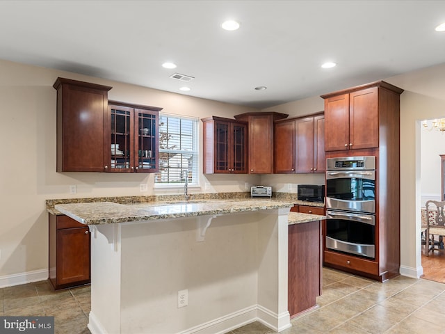 kitchen featuring light stone countertops, a breakfast bar, a kitchen island, and double oven