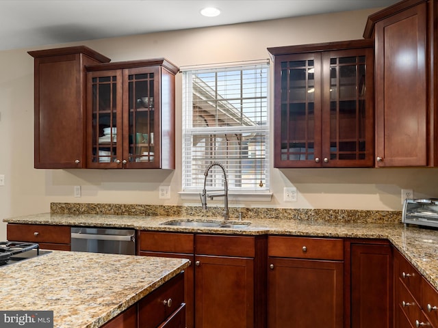 kitchen featuring light stone countertops, stainless steel dishwasher, and sink