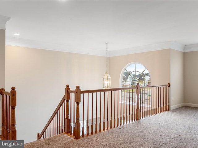 hallway featuring carpet flooring, crown molding, and a chandelier