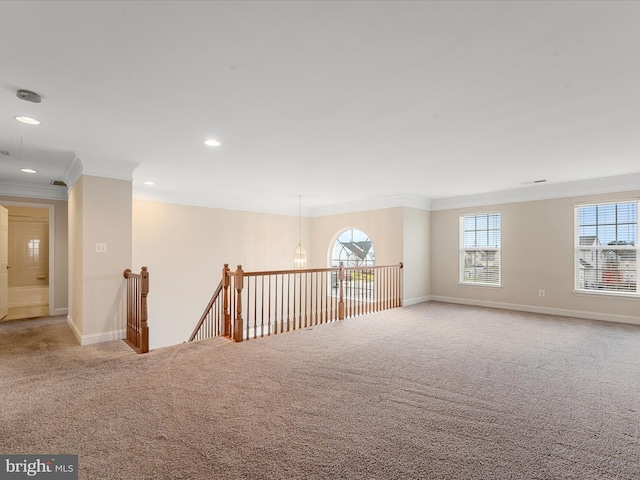 carpeted empty room featuring a wealth of natural light and ornamental molding