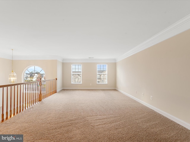 carpeted spare room featuring crown molding and a notable chandelier