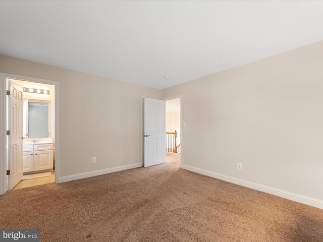 unfurnished bedroom featuring ensuite bath and light carpet