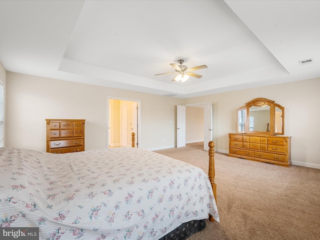 carpeted bedroom featuring a tray ceiling and ceiling fan