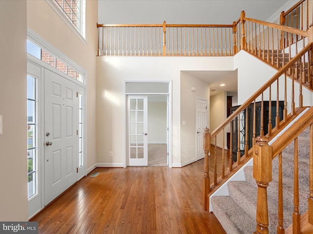 foyer entrance with wood-type flooring, a wealth of natural light, and a high ceiling