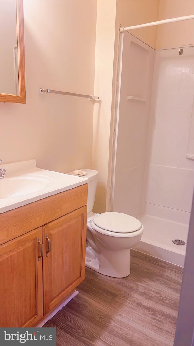 bathroom with hardwood / wood-style flooring, toilet, a shower, and vanity