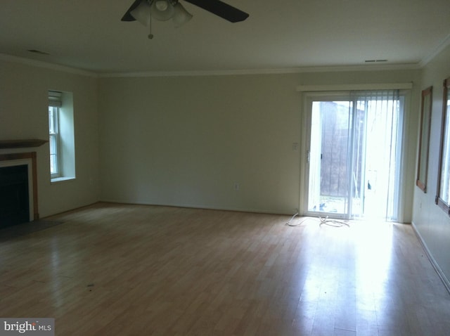 unfurnished living room featuring ceiling fan, light wood-type flooring, crown molding, and a wealth of natural light