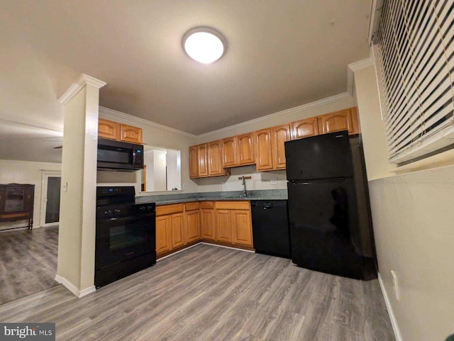 kitchen with black appliances, ornamental molding, and hardwood / wood-style flooring