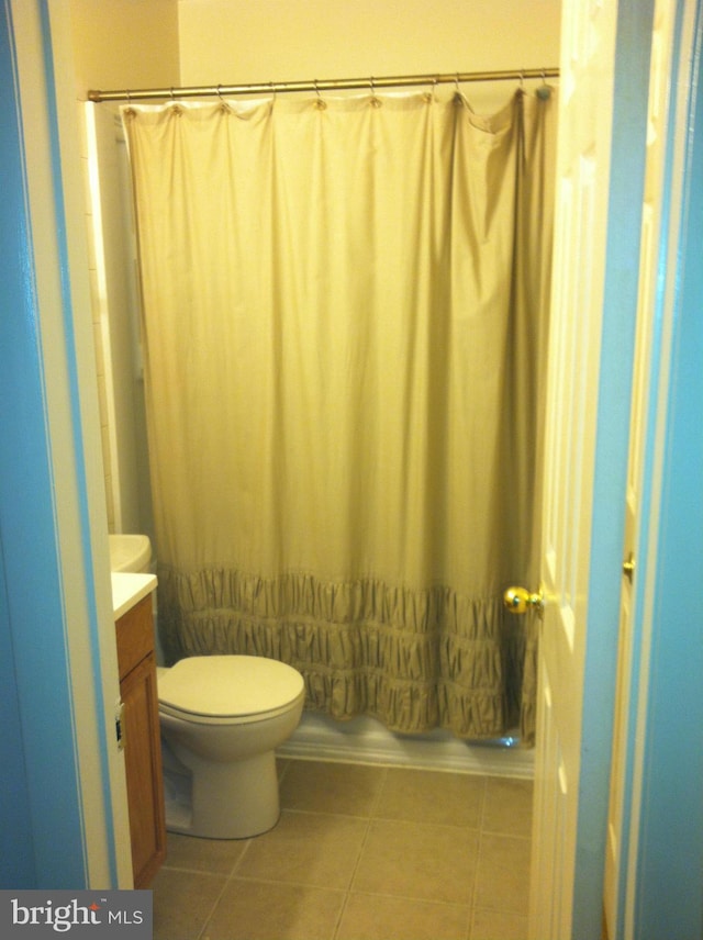 full bathroom with shower / bath combo with shower curtain, tile patterned flooring, vanity, and toilet