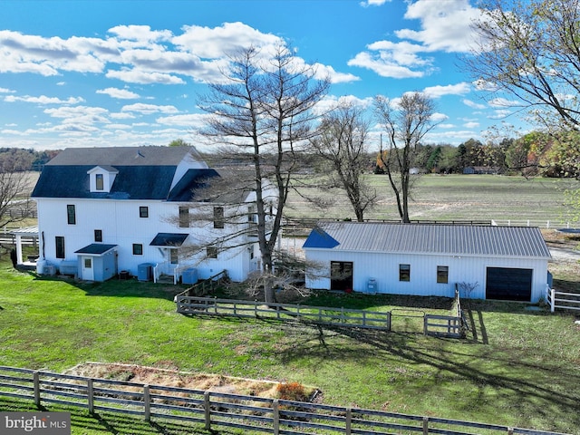 back of property with a rural view, central AC, a lawn, and an outdoor structure