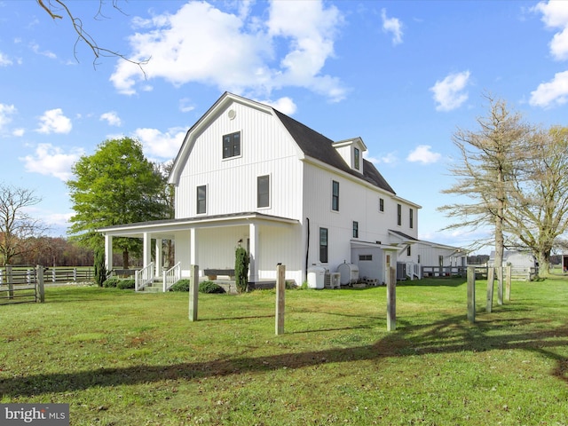 rear view of property with covered porch and a lawn