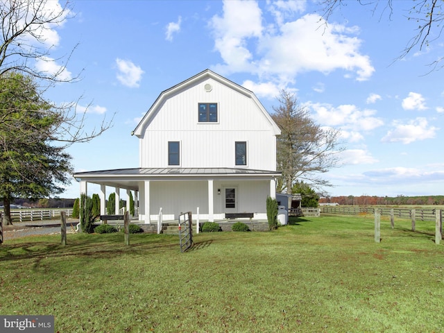 back of property featuring a yard, a rural view, and covered porch