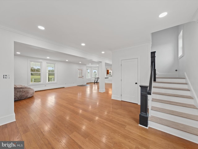 unfurnished living room featuring ornamental molding and light wood-type flooring