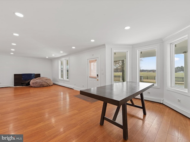 recreation room with ornamental molding and light hardwood / wood-style floors