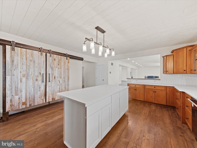 kitchen featuring dark hardwood / wood-style flooring, decorative light fixtures, a barn door, and a kitchen island