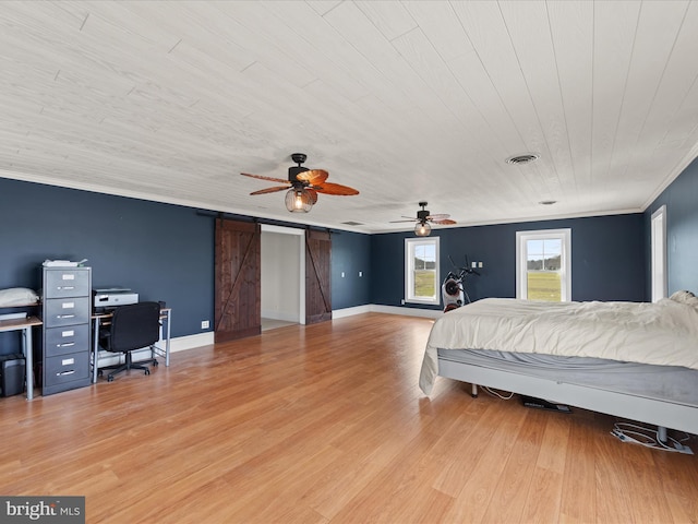 bedroom featuring ceiling fan, ornamental molding, a barn door, and light hardwood / wood-style flooring