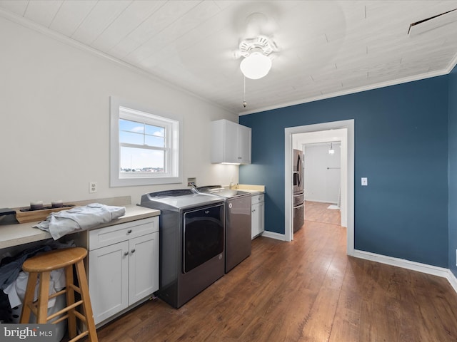 washroom featuring ceiling fan, dark hardwood / wood-style floors, cabinets, ornamental molding, and washing machine and clothes dryer