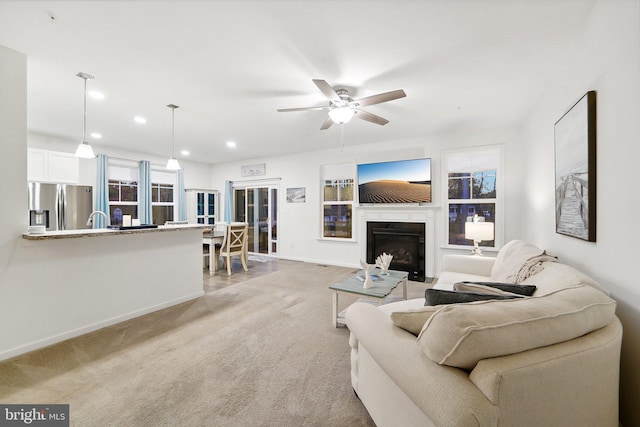 carpeted living room with ceiling fan and sink