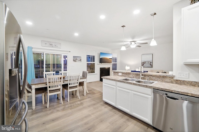 kitchen with white cabinets, sink, hanging light fixtures, ceiling fan, and stainless steel appliances