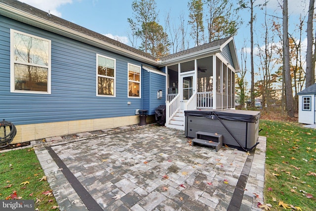 rear view of house with a sunroom, a patio, and a hot tub