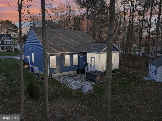 back house at dusk with a lawn